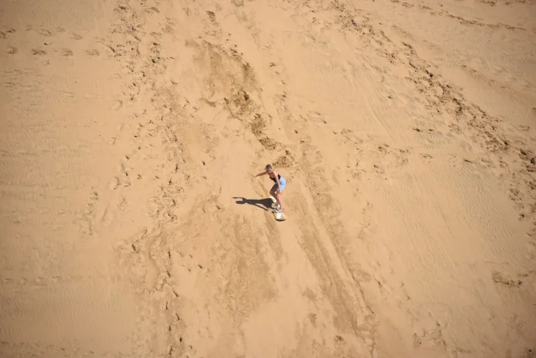 Young woman ventures up the steep and long slope in the small Sahara of Morocco