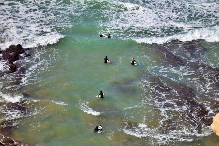 Surfers on their way into the water via the rocky entrance at Killer Point