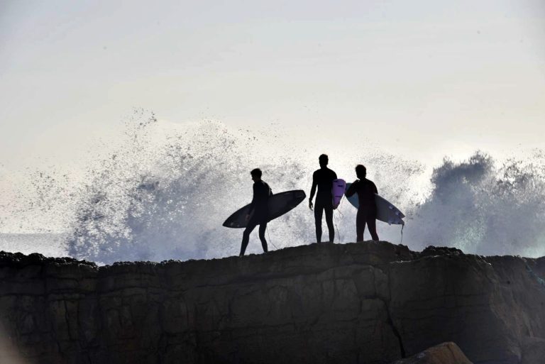 Surfers heading into the water above the rocks at the Boilers surf spot