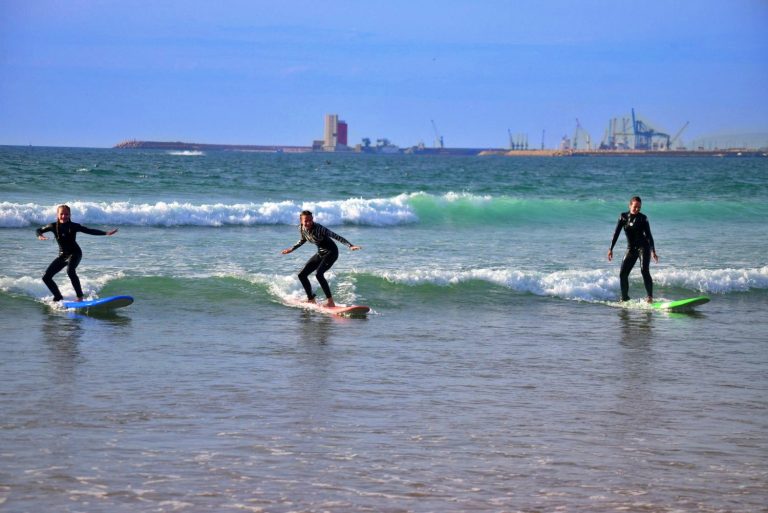 Mother surfs a green wave with her two daughters on the beach in Agadir