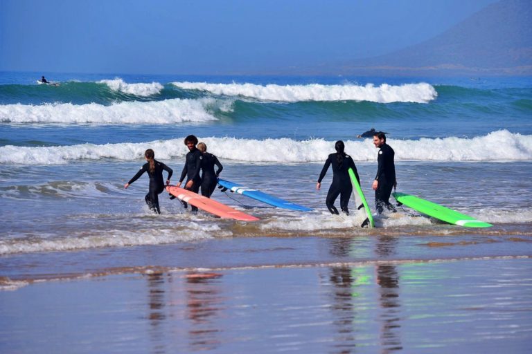 Family of four goes into the water with the surf instructor to surf the next waves