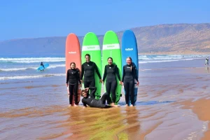 Family poses after surfing lesson with surfboard behind their backs
