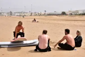 The surf course participants sit on the beach in Agadir and receive a theoretical introduction