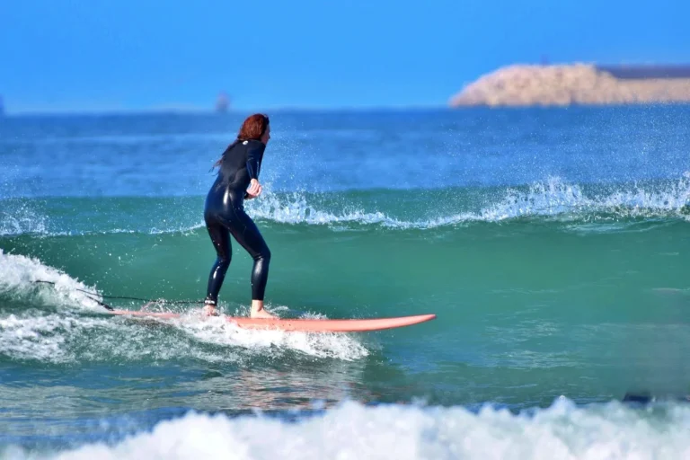Young woman rides a green wave at the surf spot Palm Beach in Agadir