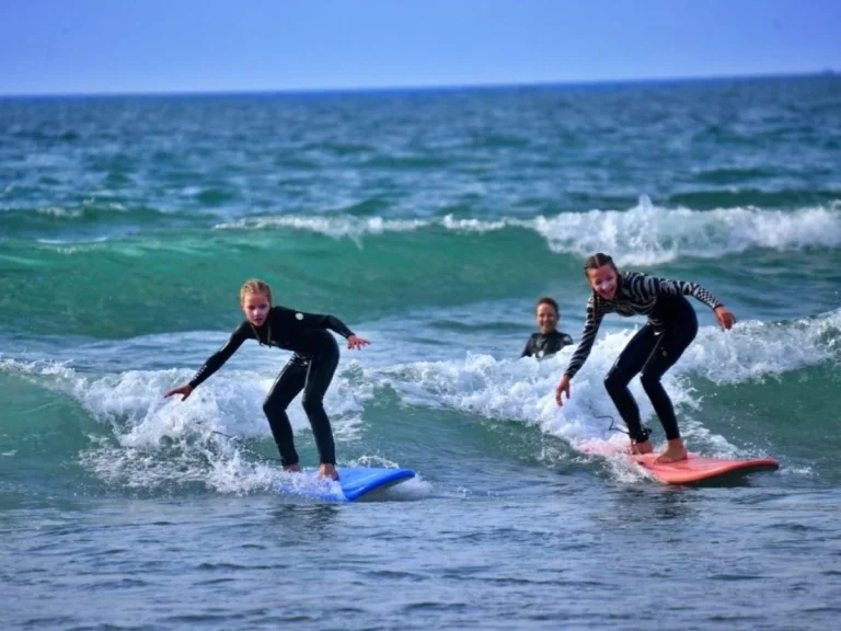 Two girls surf enthusiastically on their first waves at Agadir beach