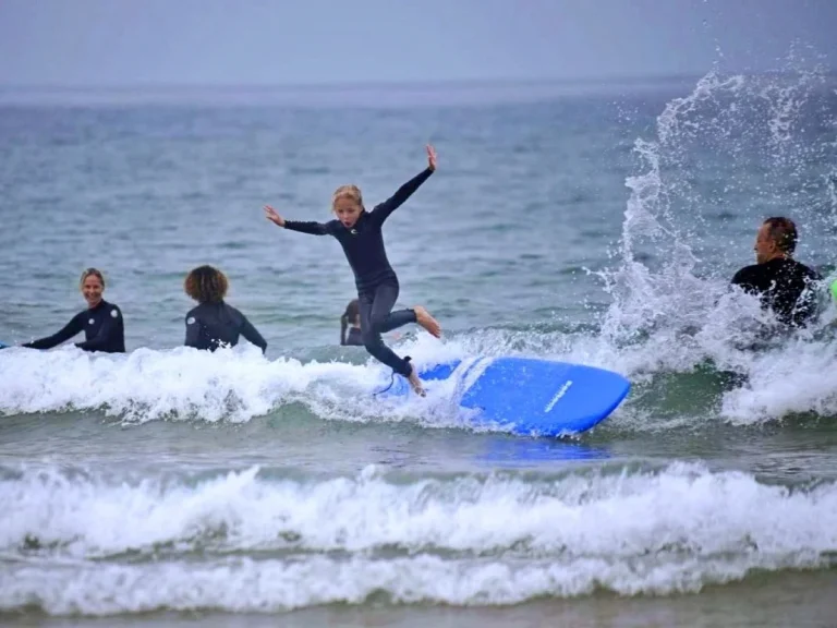 Little girl jumps joyfully from surfboard