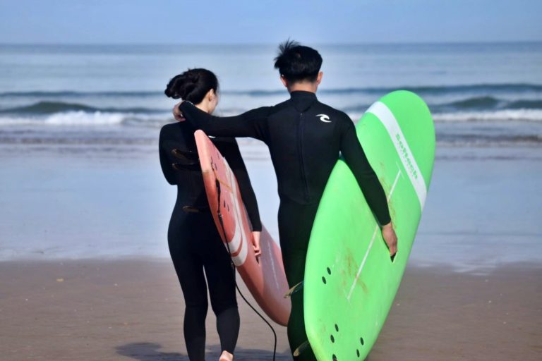 Young couple arm in arm on their way to surfing