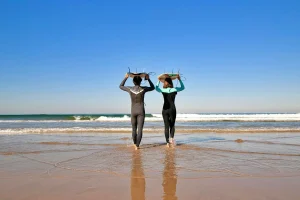 A couple on their way into the water, both carrying the surfboard over their heads