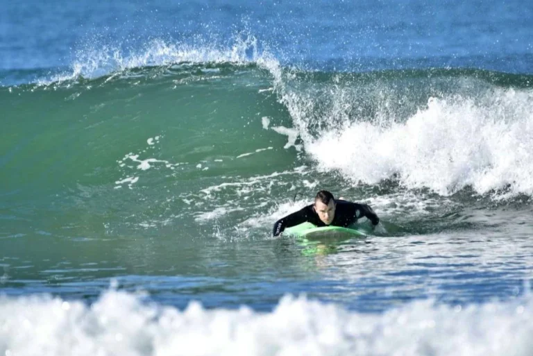 Surfer paddles a green wave