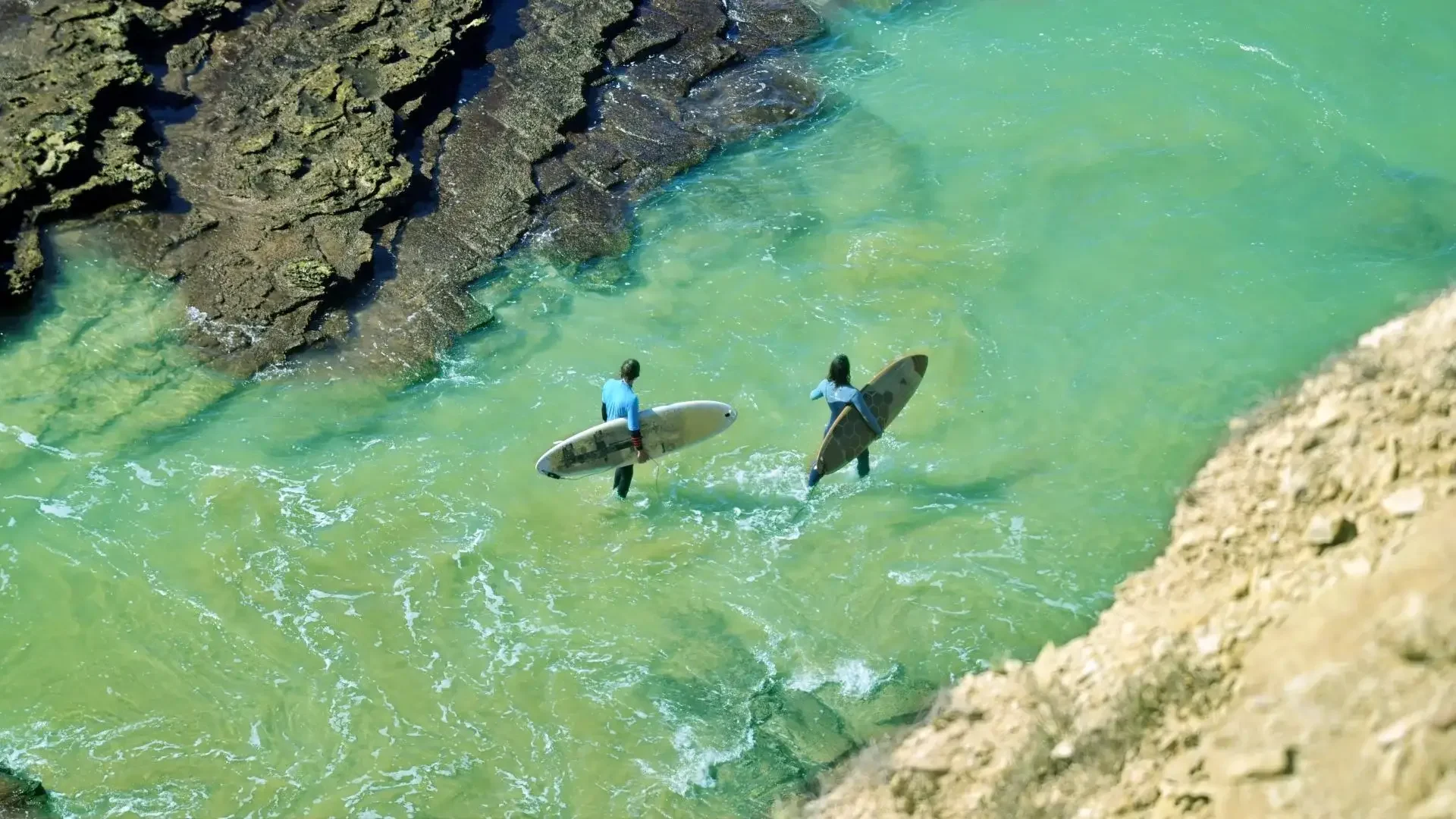 Two surfers heading into the water at the surf spot Killer Point in Taghazout Morocco